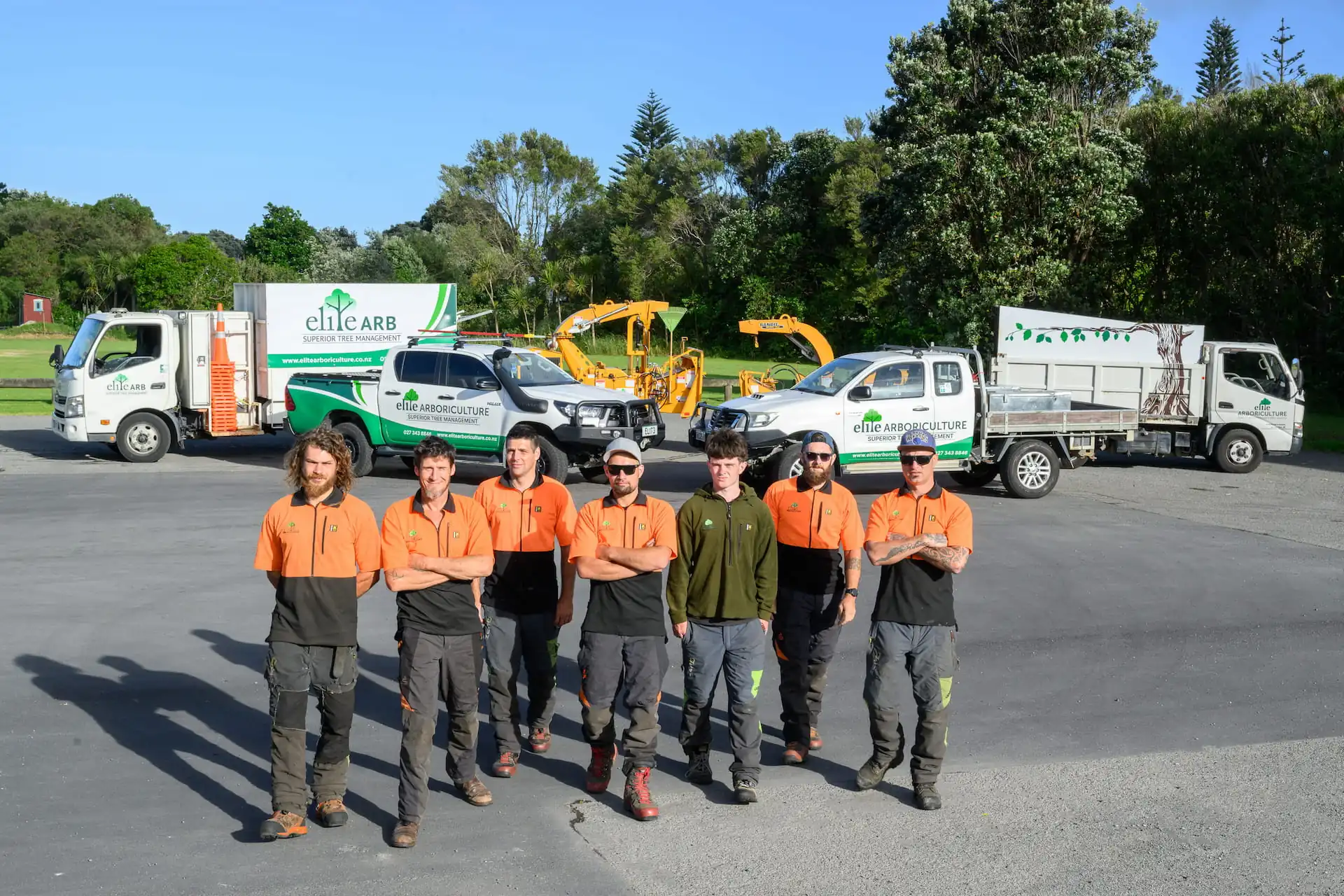A high angle landscape image of Elite Arboriculture professionals standing in front of their trucks and tools.